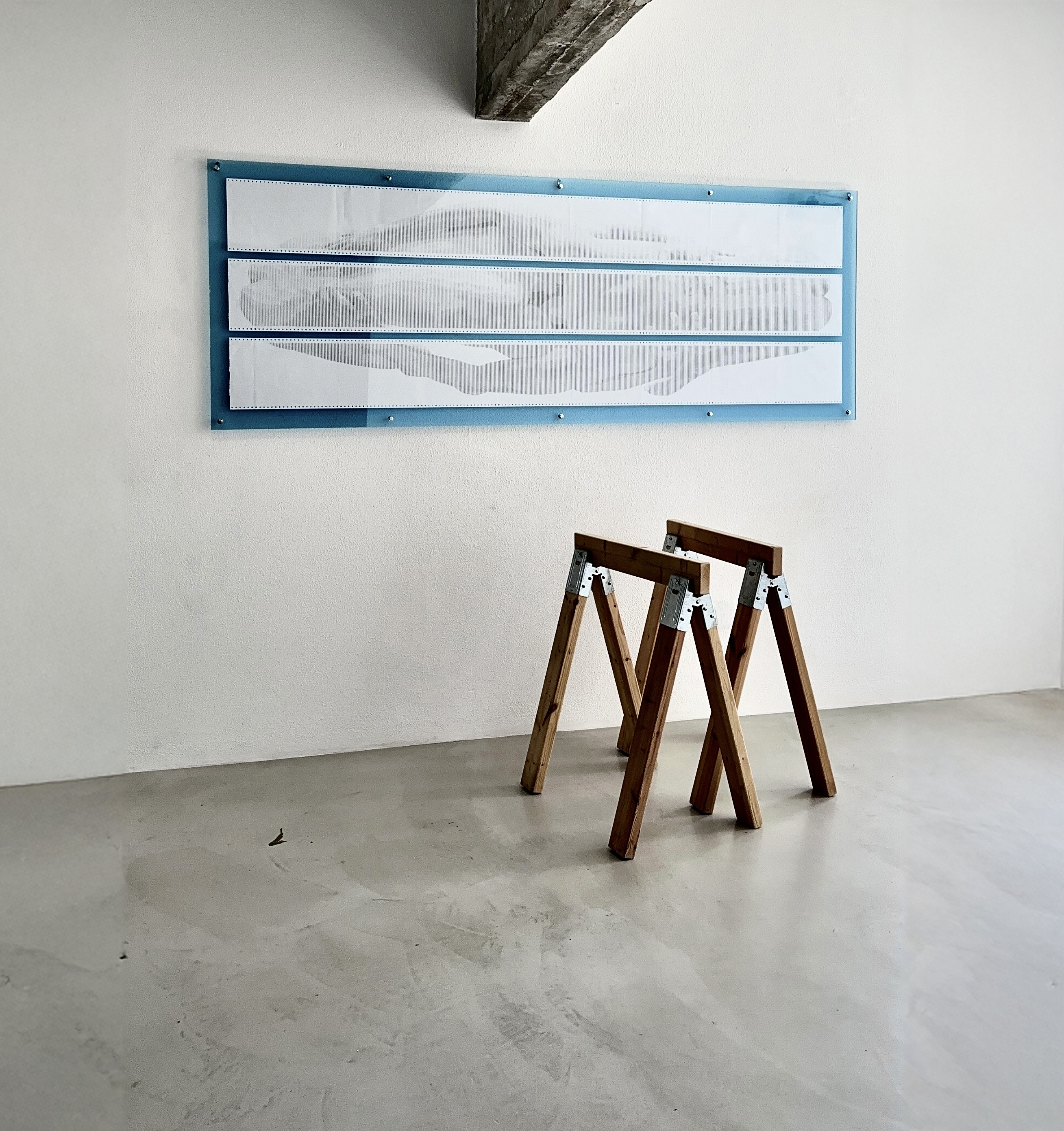 BODY.QUEUE by CHARACTERS shown with two saw horses for scale, three tall paper sheets presenting a partially obscured male figure.